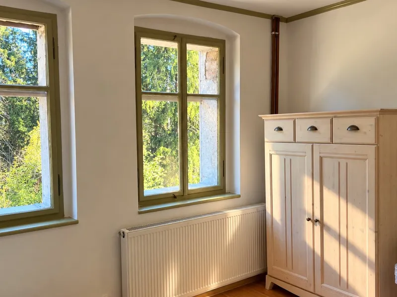 Ložnice se dvěma okny do lesa a bílou skříní